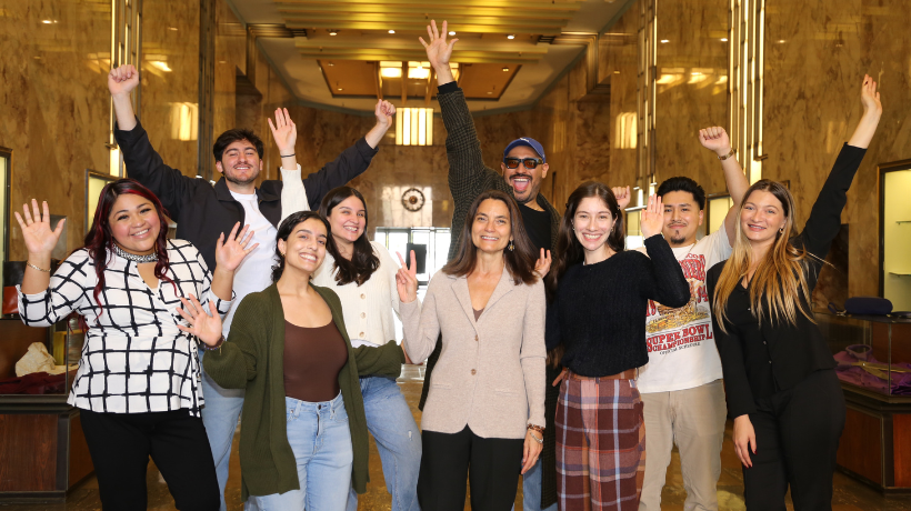 Prof. Andrea Ramos with Immigration Law Clinic students in a group with fun cheering poses in the BW Central Hall