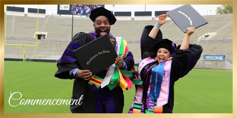 Two Southwestern graduates in regalia holding their diplomas and jumping for joy