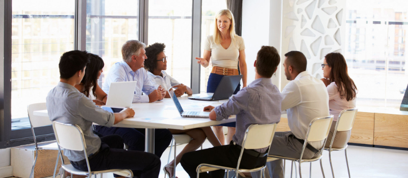 Woman speaking to colleagues at meeting table