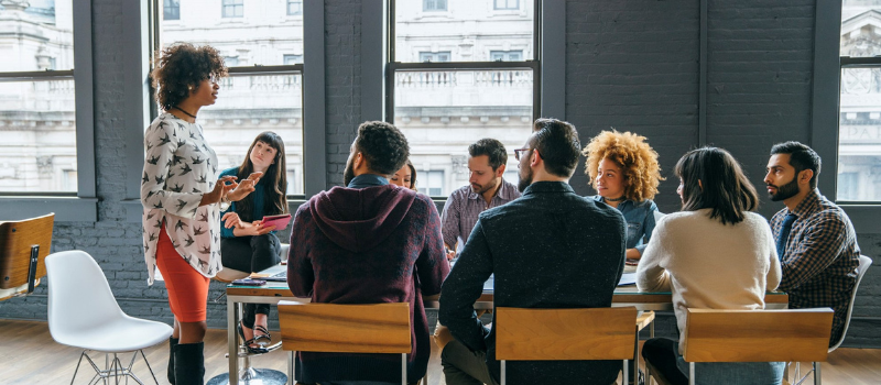 Woman speaking at head of table to group