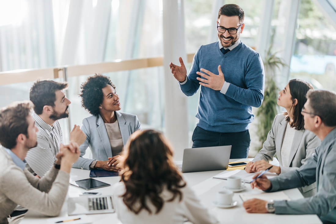 Man in business professional dress speaking to group in circle around table